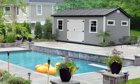 Gray storage shed with white trim by a pool